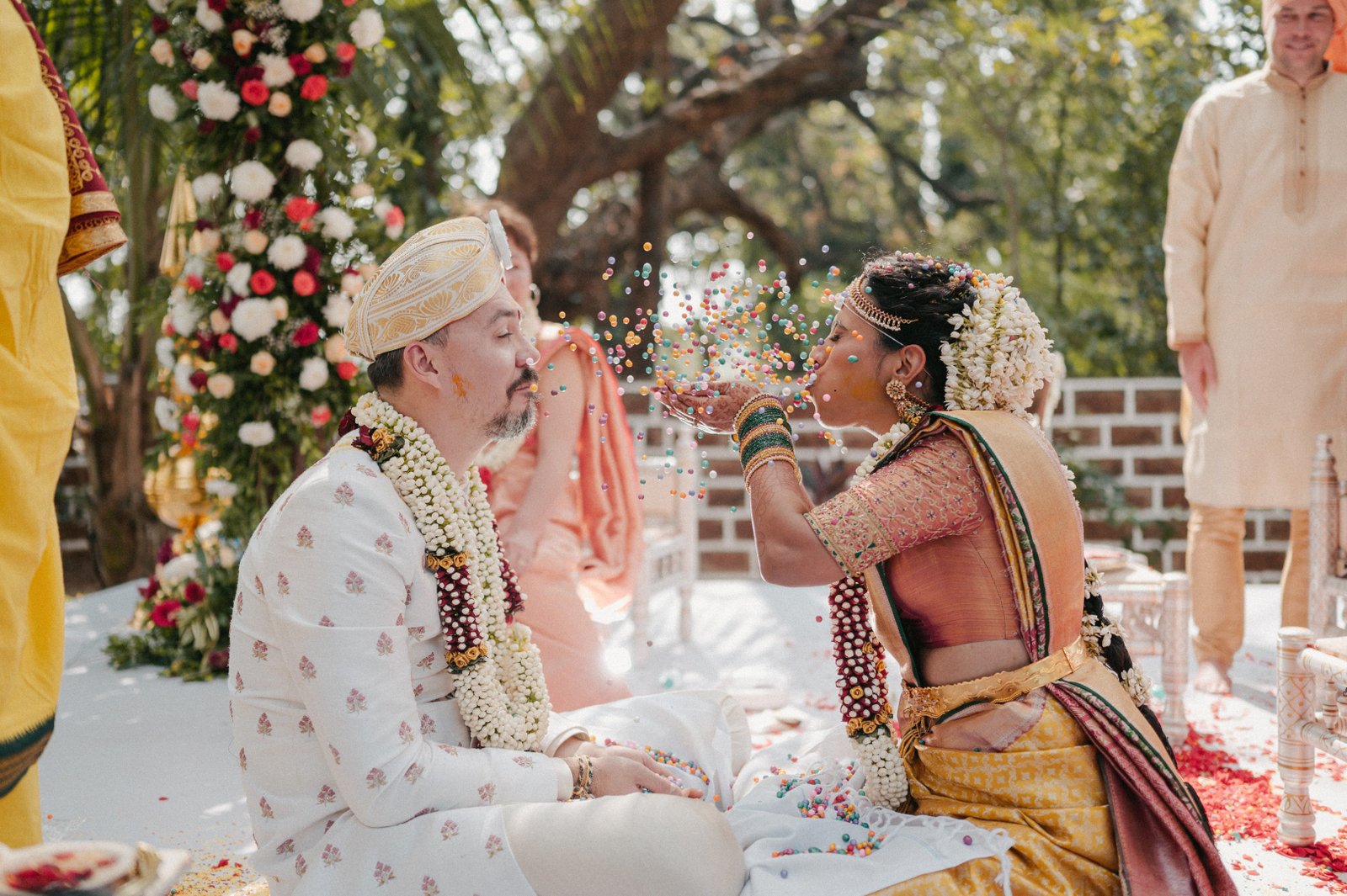 Bride and groom in traditional attire smiling at each other